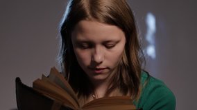 Teen girl is surrounded by books and reading. 4K UHD native video.