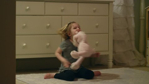 Angry young girl stomps around in her bedroom throwing, hitting and biting a stuffed animal
