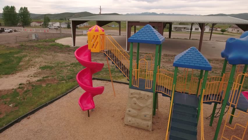 A fun aerial shot of a little boy playing at the town park on the slides and swings