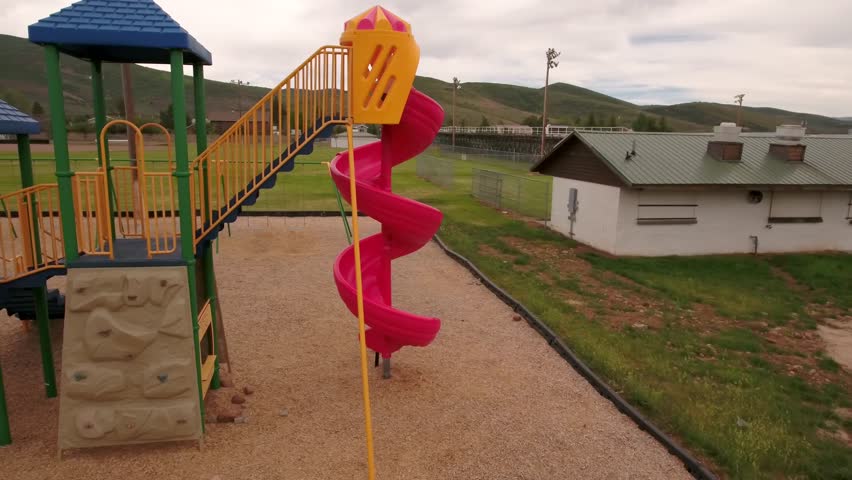 A fun aerial shot of a little boy playing at the town park on the slides and swings