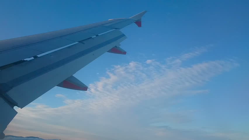 Inflight Passenger Point Of View Looking Over Wing Of Airplane . Flaps lowered, the plane banks as the pilot aligns the plane with the runway for landing. 
