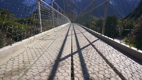  View Of Hiker's Feet Walking On Suspension Bridge At Hooker Valley Track, Mount Cook National Park, New Zealand. Camera Motion From Low Angle Sliding Upwards