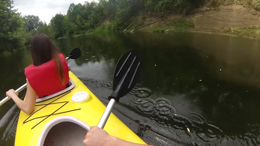Two people canoeing in the river in the beautiful green water park in the rain