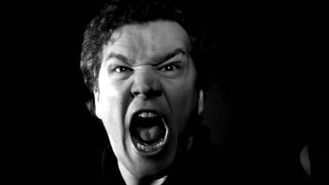 Furious yelling man in slow motion. This guy is so angry he's making an evil screaming rage face. Raging and livid, man moves in close with serious expression.