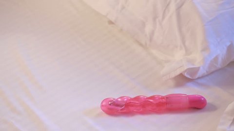 Young woman holding dildo on bed. sex toys
