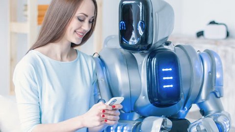 Nice cheerful woman sitting on the couch with robot