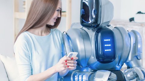 Pleasant smiling woman sitting on the couch with robot