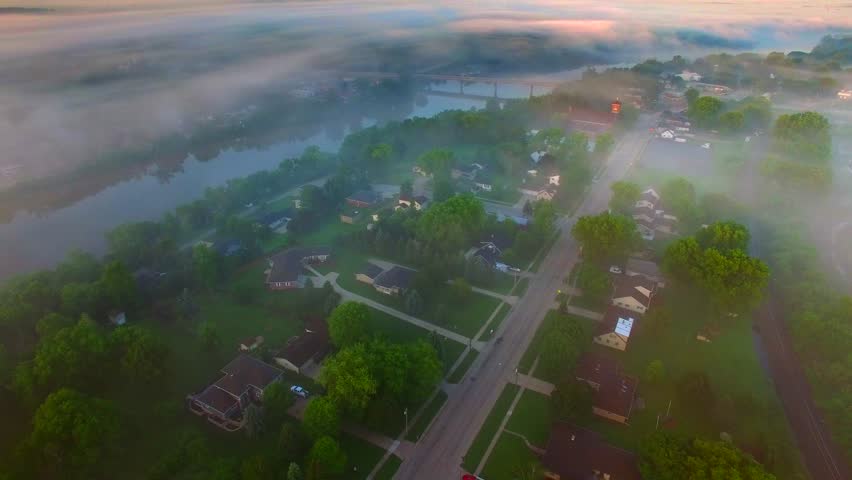 Small town America with river, bridge, under spectacular foggy sunrise, aerial view.