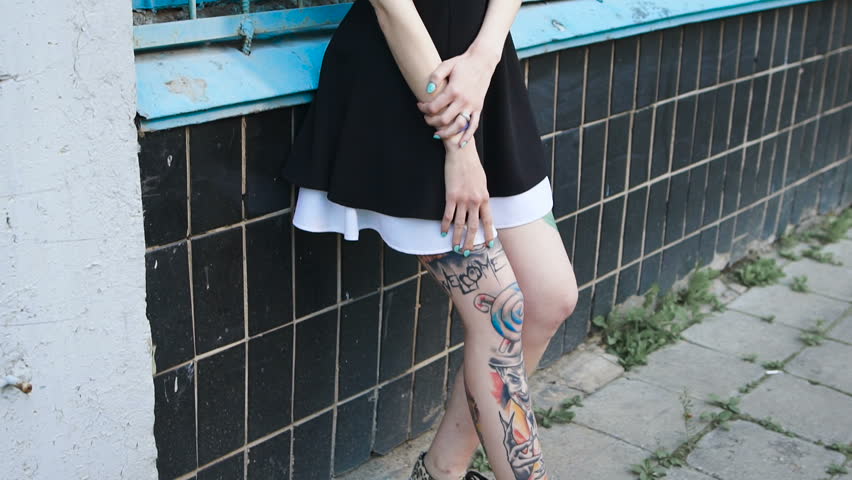 Portrait of a punk girl with tattooed feet on the street.