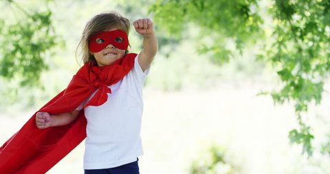 in a beautiful and happy sunny day , a little appy  dressed as a super hero makes expressions and try to fly in the colorful nature ,child laughs happy .
concept of happiness , love and nature.