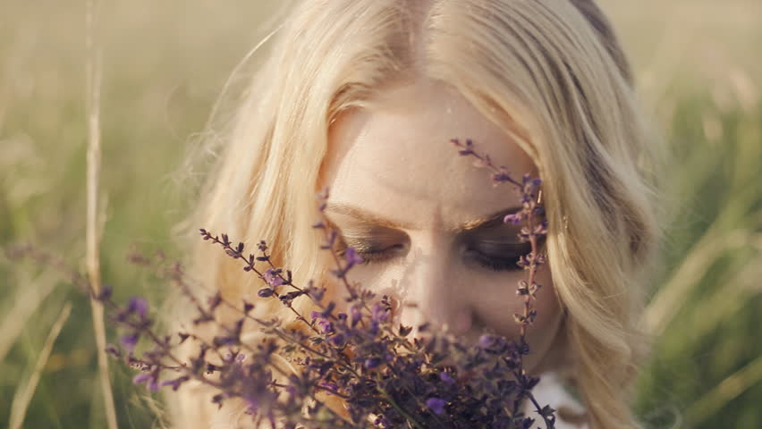 blonde girl with blue eyes smelling a herbs bouquet