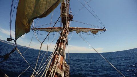 View from nose of old vintage sailing ship waving in deep blue sea with ropes and maintenance thing in air