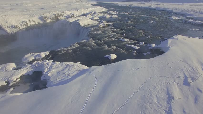 Aerial UHD video of Godafoss waterfall in northern Iceland. Shot in winter with snow on the ground and low level sunlight. 