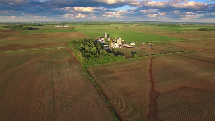 Rural Wisconsin landscape with silos, farms, fields, long shadows. Aerial view.
