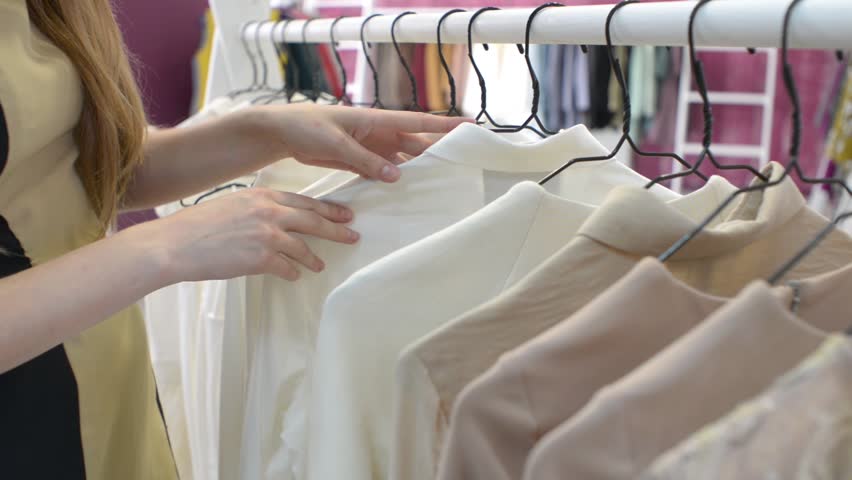 KHERSON, UKRAINE - JUNE 02, 2016: Woman brunette get shopping at store, coats, dresses, blouse on the trempels | Shutterstock HD Video #17455792