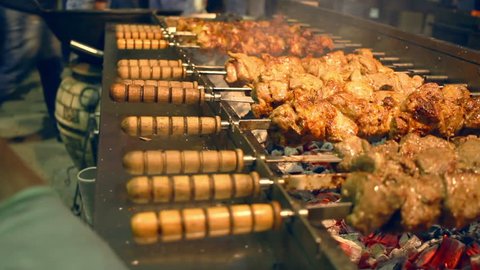 Grilled meat on skewers. Street food. Meat rotating on skewer. Food grilling on barbecue. Preparing tasty meat barbeque on skewers. Grilled meat shashlik. Shish kebab.