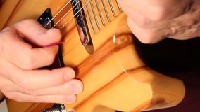 A closeup view of a guitarist playing a custom handmade electric guitar.
