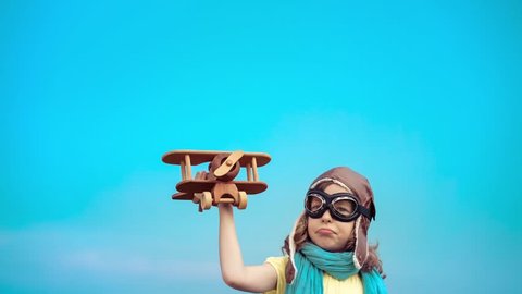 Happy kid with toy airplane. Child having fun outdoors. Kid playing in summer. Child against blue sky background. Travel and vacation concept. Imagination and freedom concept. 4K shooting Sony A7r II