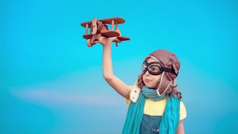 Happy kid with toy airplane. Child having fun outdoors. Kid playing in summer. Child against blue sky background. Travel and vacation concept. Imagination and freedom concept. Slow motion from 120 fps