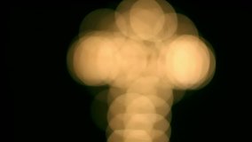 Beautiful bokeh with a cross in the black background. Circular, shallow depth of field candles. Full HD 1080p video