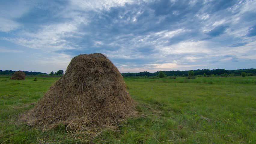 Haystack and evening clouds timelapse. Nature landscape with hay and clouds
