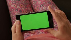 Woman relaxing in home ambient while on green screen smartphone 4K 2160p 30fps UltraHD footage - female holding mobile or tablet with greenscreen display 4K 3840X2160 UHD video