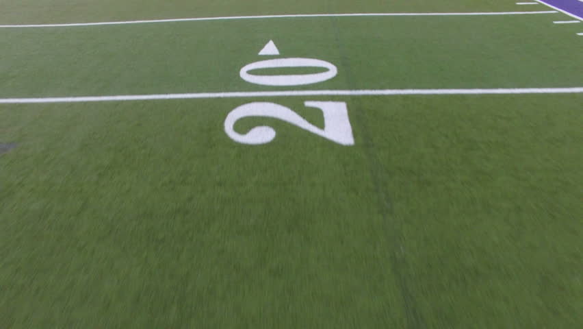 Low flying aerial over yard numbers on football field. Flying over markings on American football field. Royalty-Free Stock Footage #17479126
