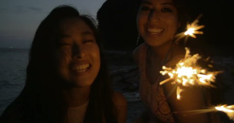 Fun International girls on the beach playing with fire work sparklers 4K.