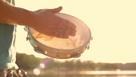 Musical instrument tambourine or pandeiro on a background of the sky at sunset