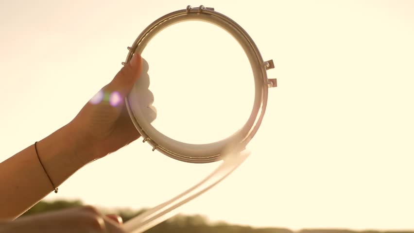 Playing a musical instrument tambourine on background sky at sunset   Royalty-Free Stock Footage #17480956