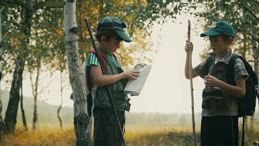 Boys travelers with backpacks studying the route map in a sunny summer day.