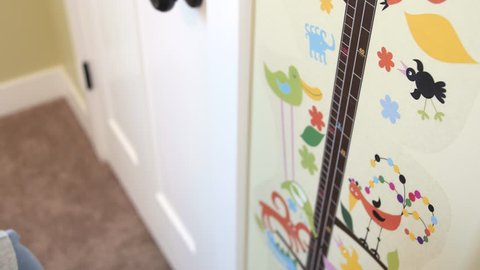A dad measures his preschool aged soon against a wall decal to see how tall he is