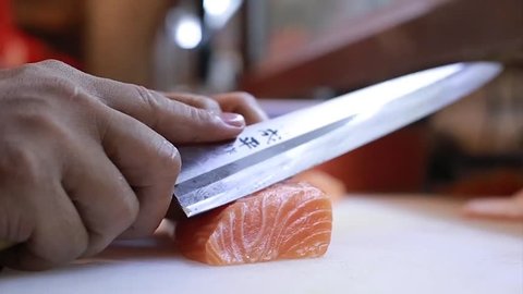 Sushi Chef Slices fresh Salmon on the sushi bar.  A sushi-man slicing a salmon steak with his Japanese knife. Preparing sushi nigiri fish. Japanese cuisine recipes.
