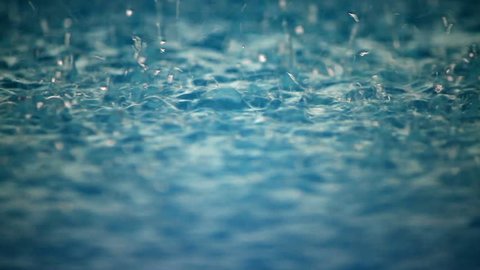 Close up of heavy rain drops on the surface of a swimming pool