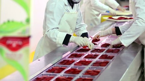 Workers sorting and packing dry meat in the food factory. Packaging of dry meat on the conveyor belt