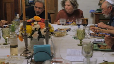 Hand held of a group of people enjoying their dinner at a celebration such as a dinner party, family event, religious ceremony, or passover seder.