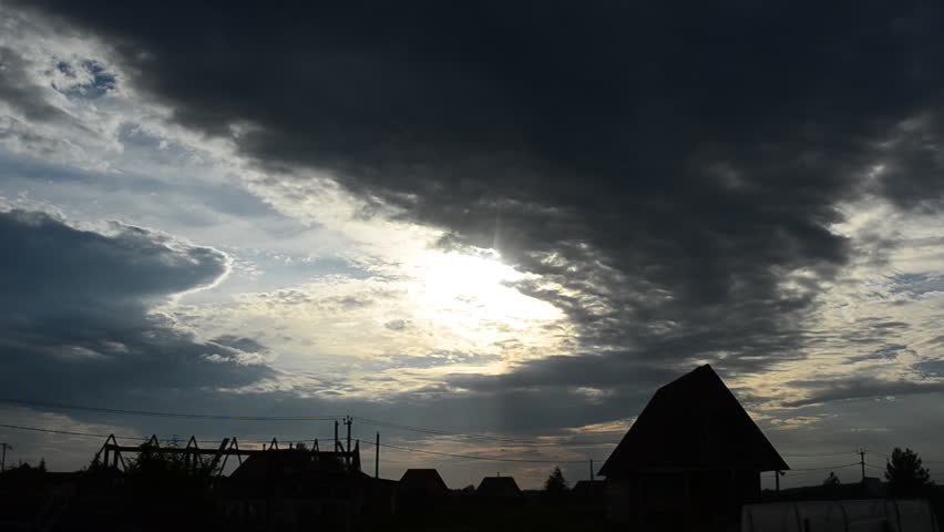 Storm cloud over a farm house at sunset.