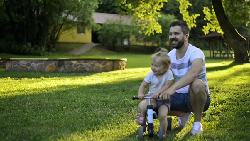 Father with his little daughter on bicycle pushing her