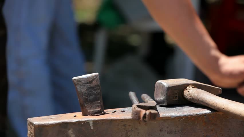 Blacksmith tools . Hammer , pliers , a chisel lay on the anvil .