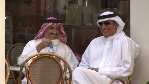 Abu Dhabi, UAE - circa 2013 - MCU of two Emirati men in traditional clothes, in a caf_, laughing over a cup of coffee.