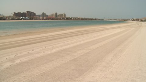 Sandy beach. Wide pan-left across a gulf sea inlet surrounded by sandy beaches and residential villas. (UAE - 2016)