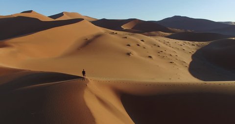 4K aerial view of male tourist walking over the sand dunes in the Namib desert,Namibia 
