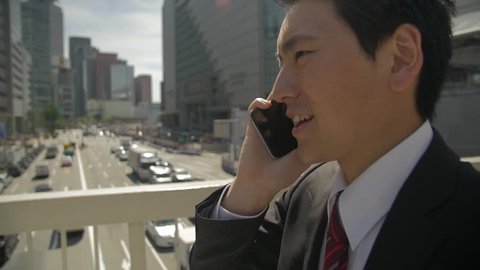 Japanese man walking with phone close up traffic background slow motion