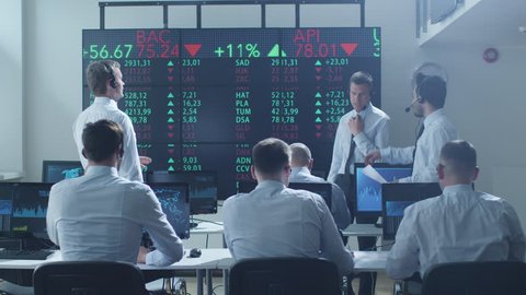 Group of Stockbrockers Actively Working using Headsets and Phones at Stock Exchange. Shot on RED Cinema Camera in 4K (UHD).