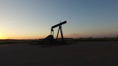Steady-cam shot of an abandoned oil well at sunset.  The camera travels smoothly around the pumping unit revealing the rest of the well site. 
