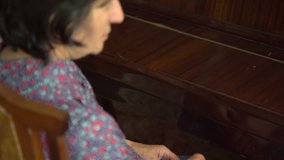 Old woman is playing the piano in home