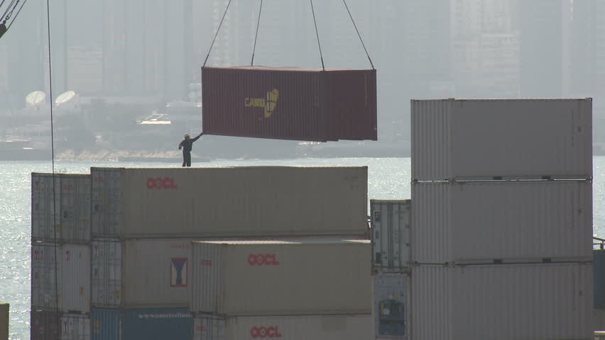 HONG KONG - CIRCA JUNE 2010: Dock worker guides shipping containers into place