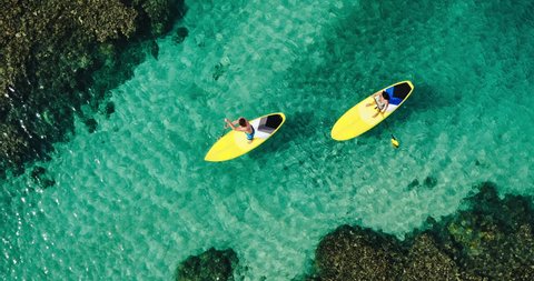 Aerial view of young couple stand up paddling on vacation