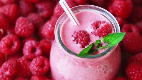 Beautiful appetizer pink raspberries fruit smoothie. Yogurt cocktail. Close up. Natural detox. Liquid ice cream. Glass of raspberry milk shake with berries background