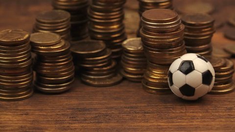 Soccer bet concept with small football on top of coin stack, making money by predicting sport results, dolly slider shot
